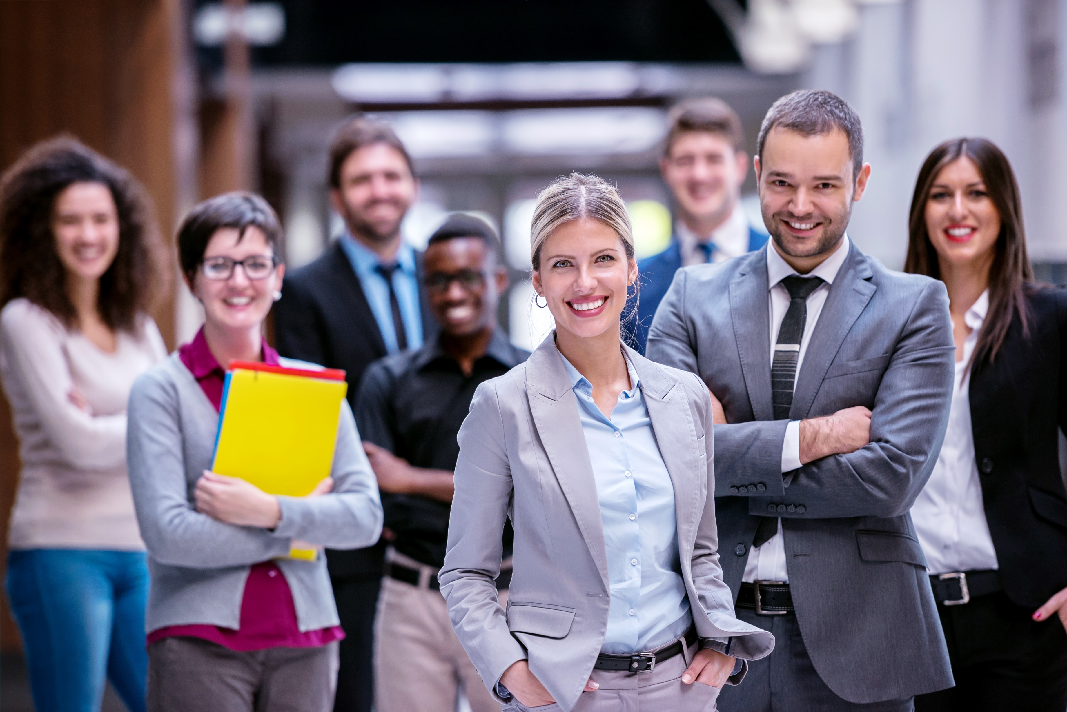 The Travel Mania team smiling together, a woman in a light gray suit standing at the front