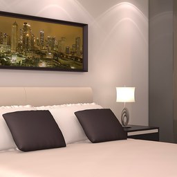 A hotel bedroom with a neatly made bed and a framed city skyline picture