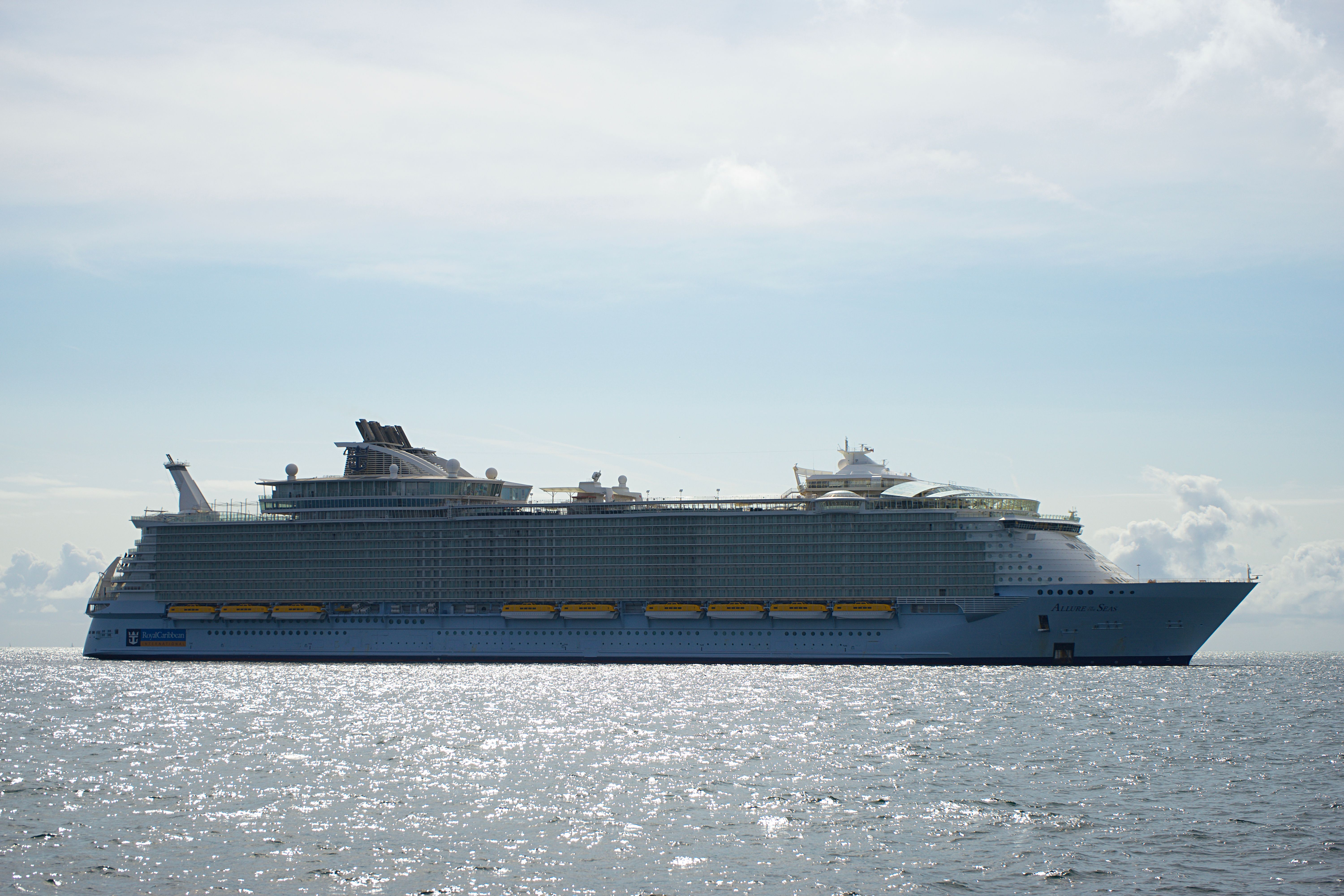 White cruise ship sailing through a dramatic coastal landscape