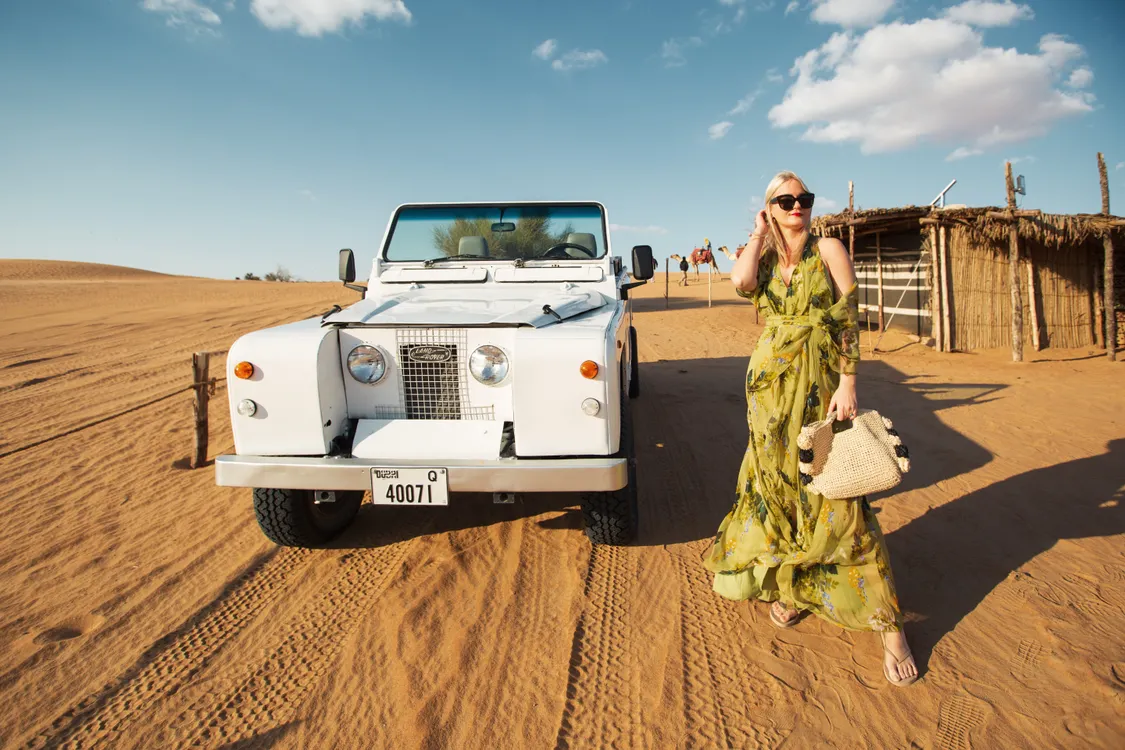 Traveler beside an off-road vehicle in Dubai's desert dunes